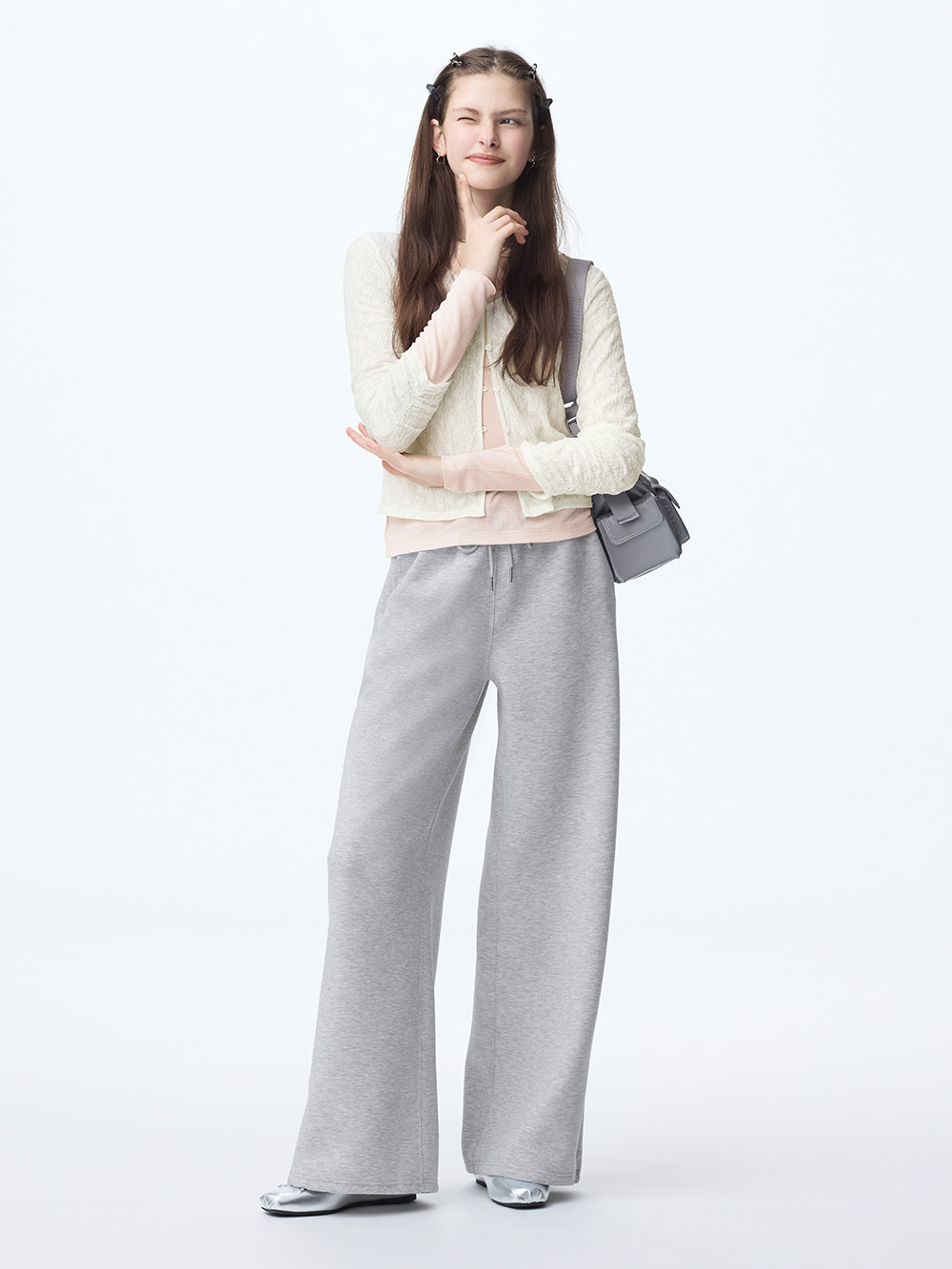 Cream cardigan layered over a pale pink top with wide gray sweatpants, silver ballet flats and a small gray bag