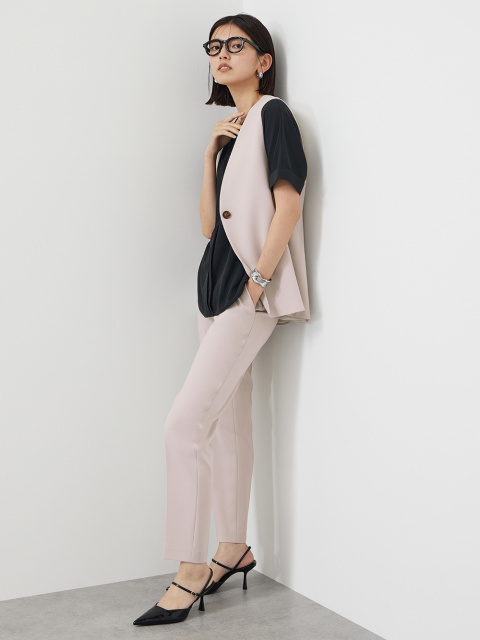 ベージュのジレとパンツのセットアップに、黒のトップスを合わせたコーデ