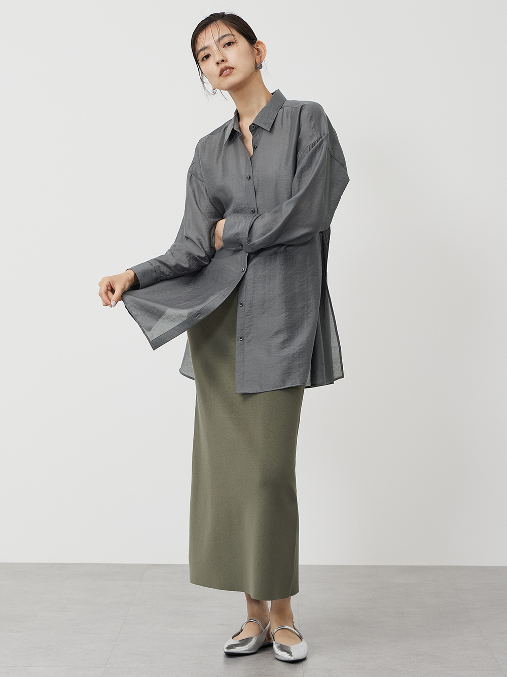 グレーのシアーシャツにニットスカートを合わせたコーデ