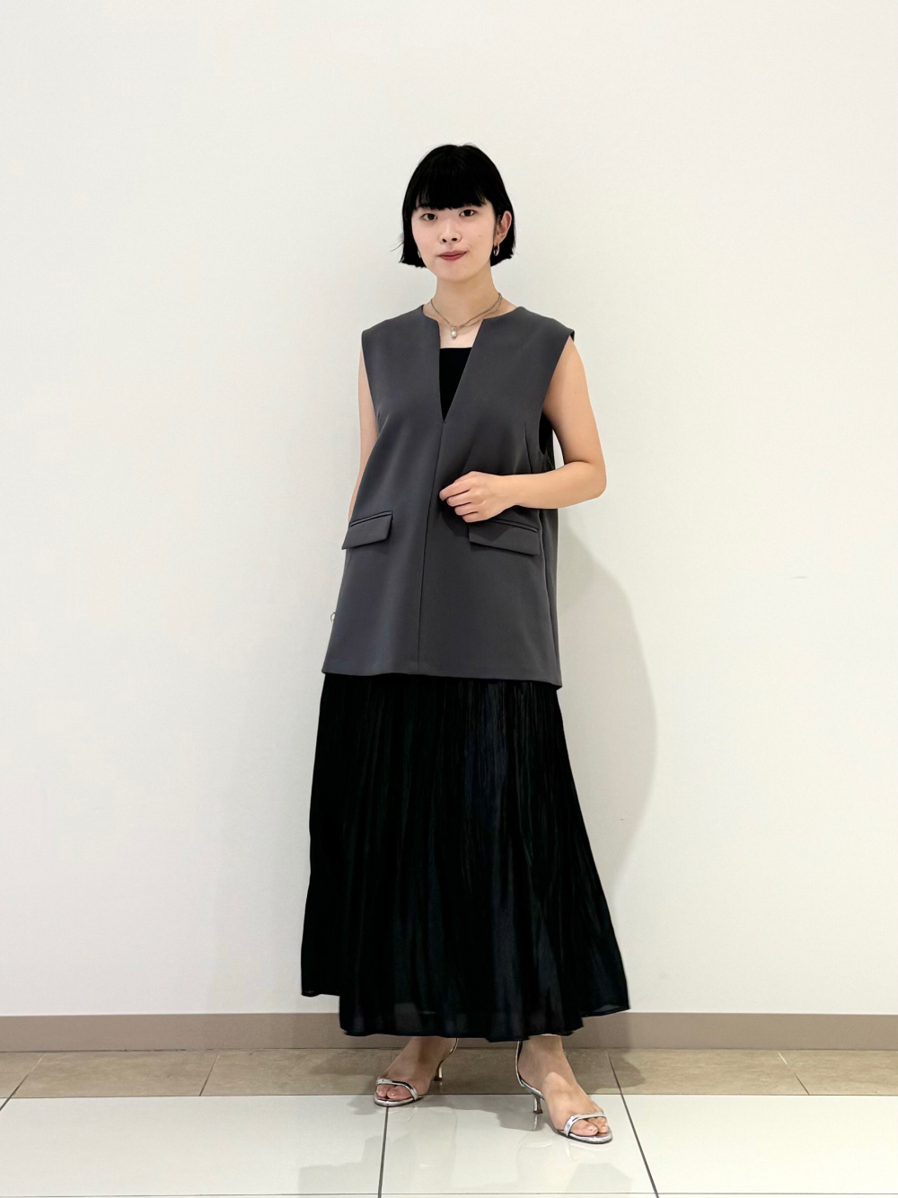 ダークグレーのベストに、黒のワンピースを合わせた夏のきちんと服