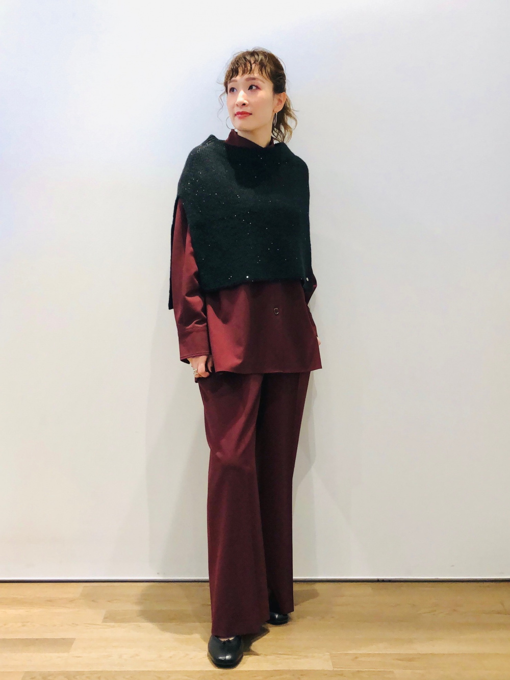 ワインレッドのセットアップに黒のケープをレイヤードしたコーデ