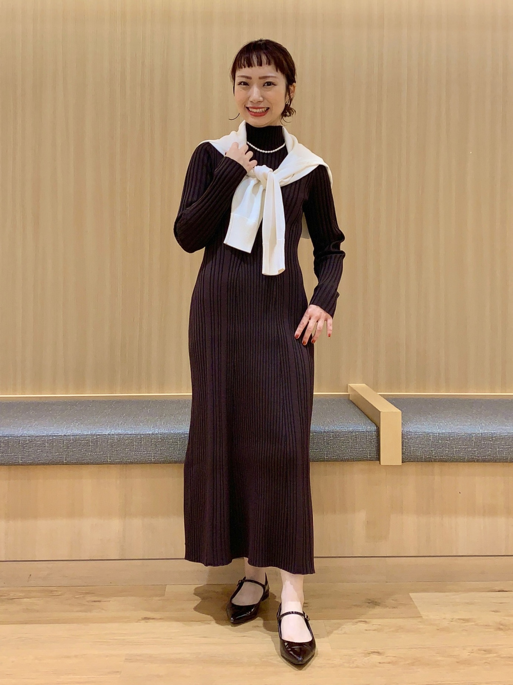 ブラウンのワンピースに差し色のセーターを肩掛けしたコーデ