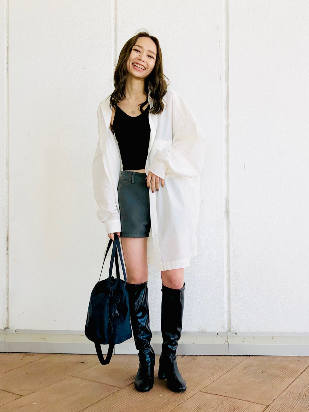 Oversized white button-up worn open over a fitted black tank with black knee-high boots